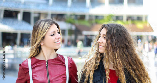 Two female friends meeting outdoor and talking