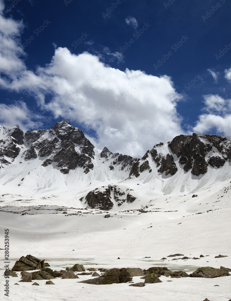 Plateau in mountains with frozen lake covered snow and blue cloudy sky