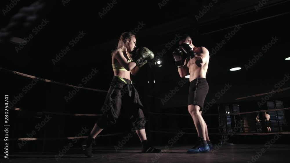 Young athletic girl kickboxer is training with her coach a strong caucasian man Young athletic girl kickboxer is training with her coach a strong caucasian man