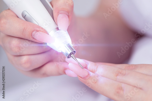 Woman filings nails with electric nail file at home