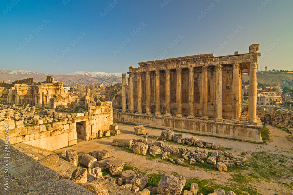 Lebanon - Baalbek (Heliopolis) - Massive ruins of the Temple of Bacchus and the part of the Temple of Jupiter in an impressive ancient archeological temple complex with snow capped peaks in a far