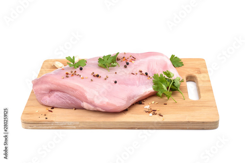 Raw turkey fillet with parsley and spices on a wooden cutting board over white background.