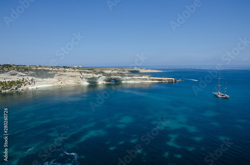 Boat with landscape with Mediterranean Sea with blue water and white rocks in Malta near Marsaxlokk, Saint Peter Pool.