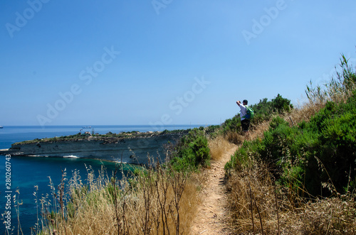 Man making photo on Munxar path. Nature with Mediterranean Sea with blue water and white rocks in Malta near Marsaxlokk  Saint Peter Pool.