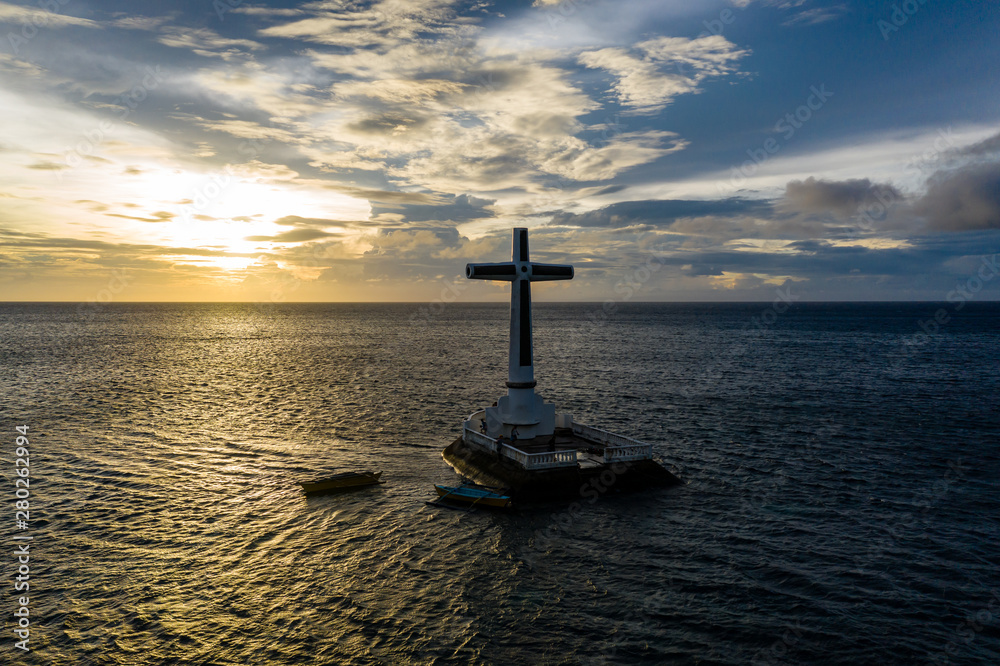 Aerial view of a large cross at sunset on a tropical ocean (Sunken Cemetery, Camiguin, Philippines)