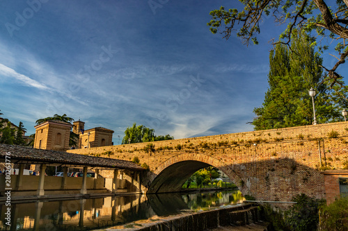 The ancient wash-house and the masonry bridge over the river, in the medieval village of Bevagna. Perugia, Umbria, Italy. Blue sky at sunset. Trees and vegetation. The reflection on the water surface.