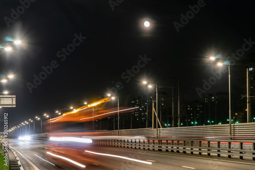 The moon rising over the illuminated highway and the night city,