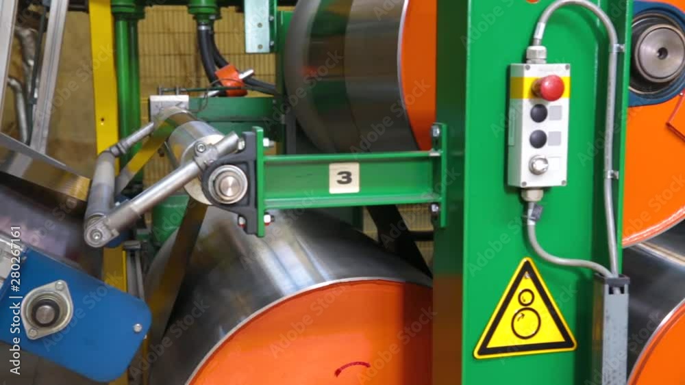 Modern machines at tire factory prepare rubber tape for further production of automobile tires. Large rubber tape reels for tire production. Rubber band is heated on the industrial drums for molding.