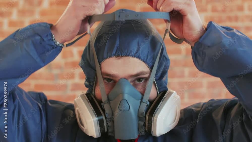 Young bearded man wearing protective workwear, mask and glasses. Close up portrait
