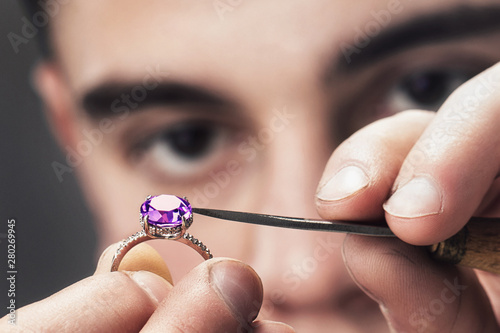Jewelry master examines the gold ring for defects, close-up photo