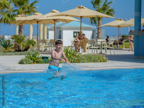 Cute European boy is enjoying his summer vacations. He is having fun in the swimming pool. © Artem