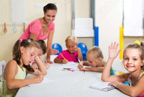  children making writing exercises with help of teacher in class