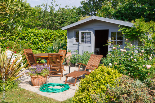 Shed with flowered terrace and wooden garden furniture