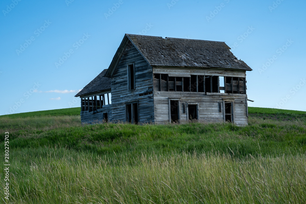 Decaying, abandoned spooky old farmhouse shack in the rolling hills of the Palouse region of Washington State