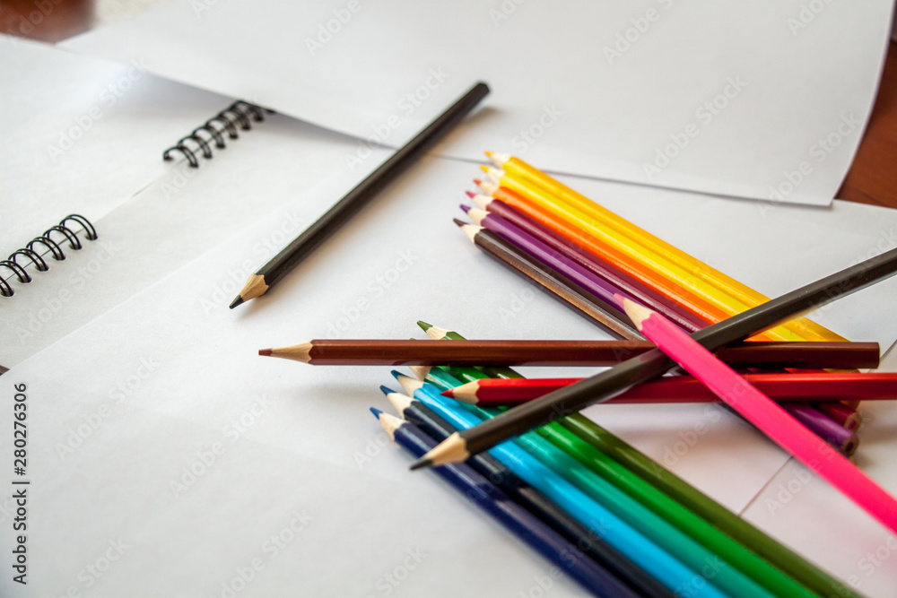 colored pencils are lying on white sheets of paper colored pencils are lying on white sheets of paper