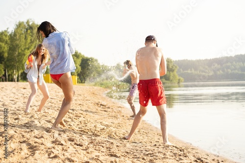Happy people with water guns have fun on the beach © opolja