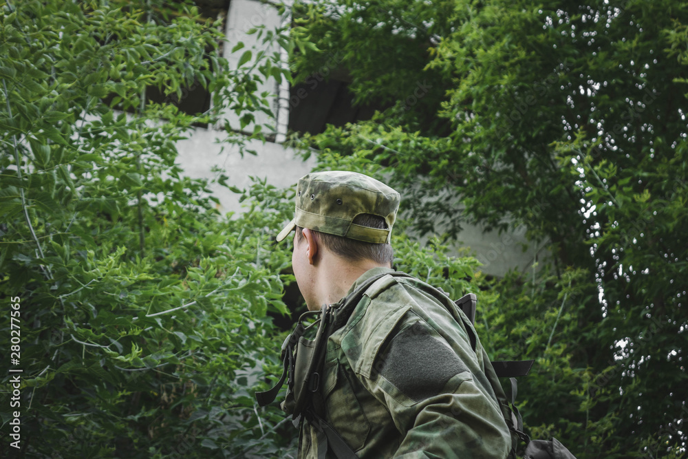 the military looks in the direction of an abandoned house in the woods