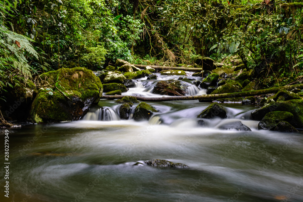 small waterfall with blurred water on the rocks in the brazilian rainforest with tropical trees around small waterfall with blurred water on the rocks in the brazilian rainforest with tropical trees around