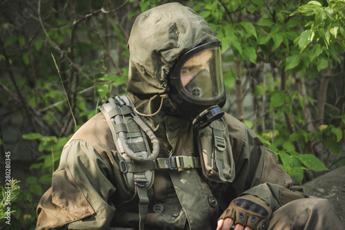 rebel man with gas mask and riffles against a in the forest.