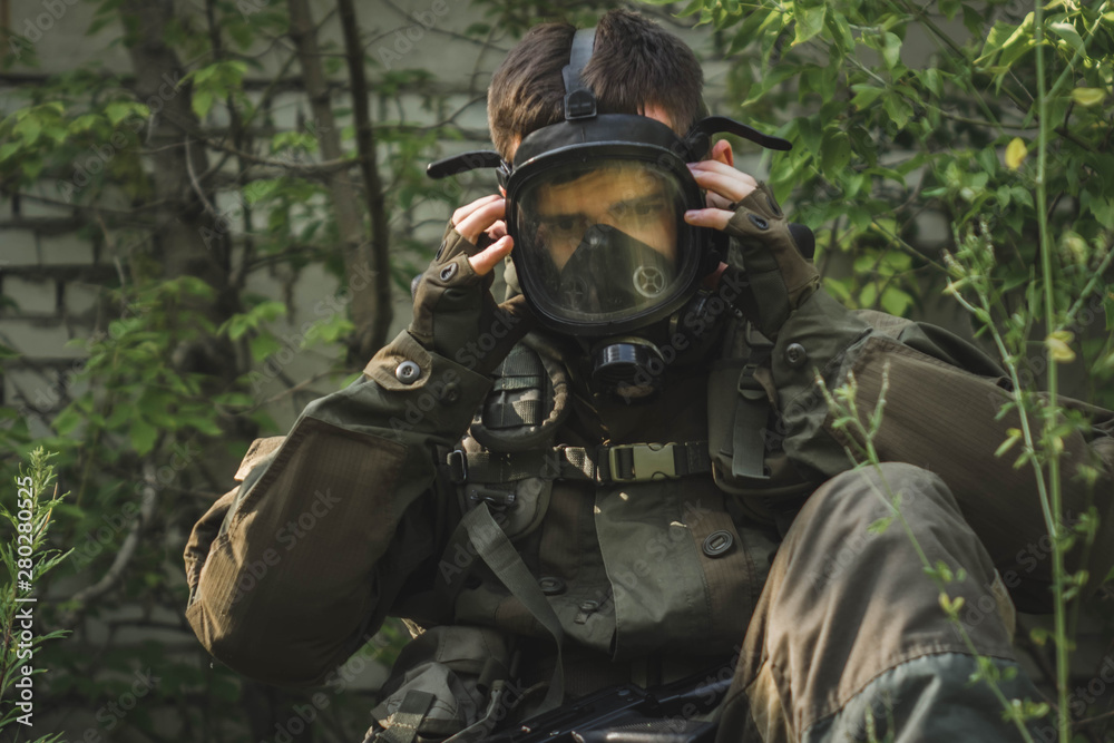 rebel man with gas mask and riffles against a in the forest.
