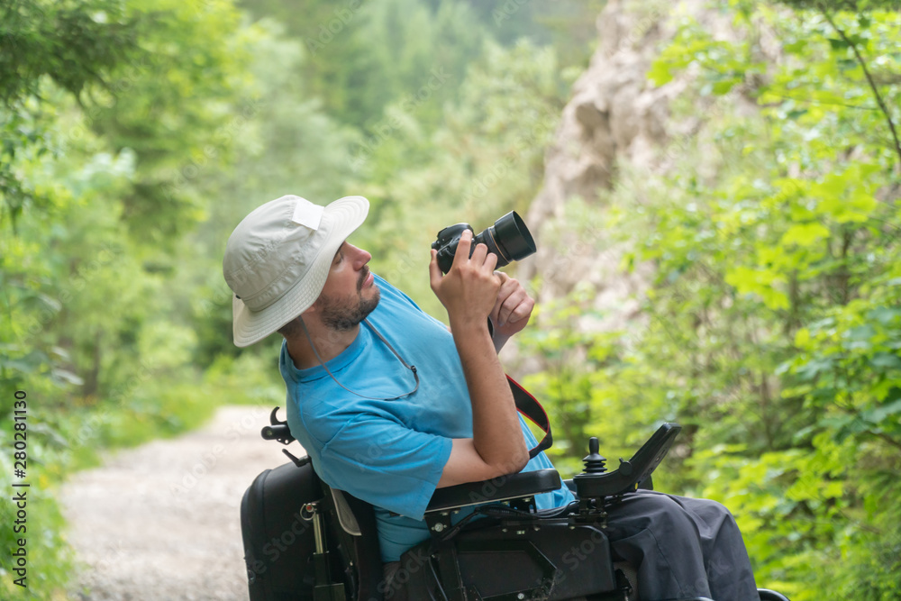 man on electric wheelchair using mirrorless camera nature, enjoying freedom and doing art
