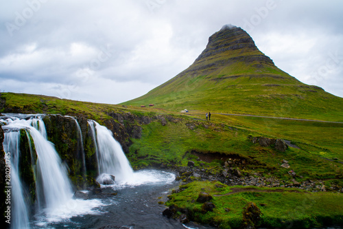 Scenic panorama view of long exposure falling water in front of Kirkjufell volcano mountain, the most iconic travel destination location in Iceland. Summer time.