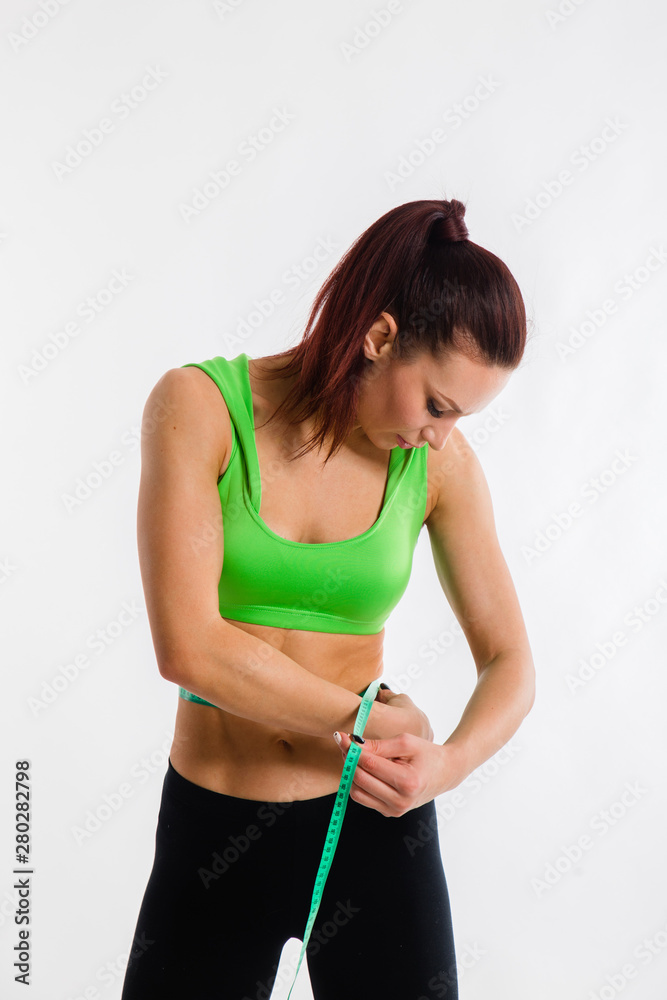 sporty young girl measures a waist with a centimeter on white background sporty young girl measures a waist with a centimeter on white background