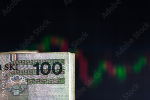 PLN (Polish New Zloty) bills on background with dynamics of exchange rates. Trading and financial risk concept