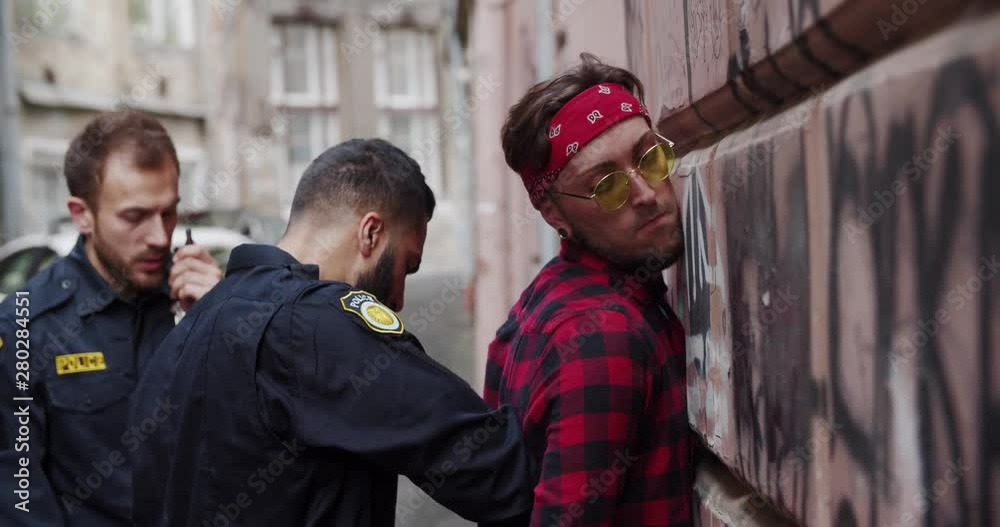 Policemen detain a drug dealer force young man to the wall search him out and put on handcuffs. Police arrest. Policemen detain a drug dealer force young man to the wall search him out and put on handcuffs. Police arrest.