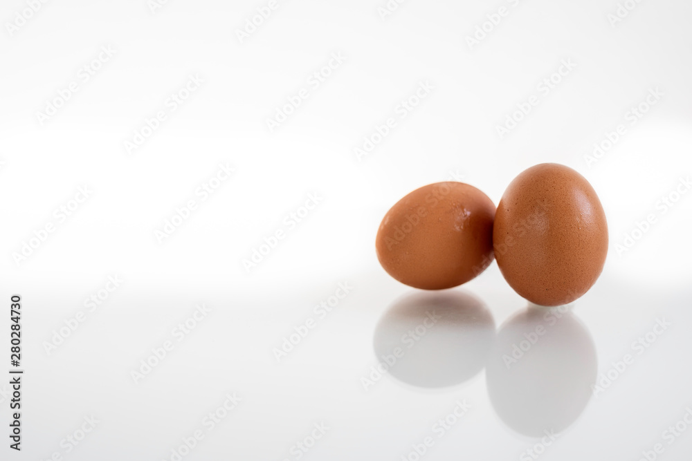 Two hen or chicken eggs isolated on white background with reflex on glass