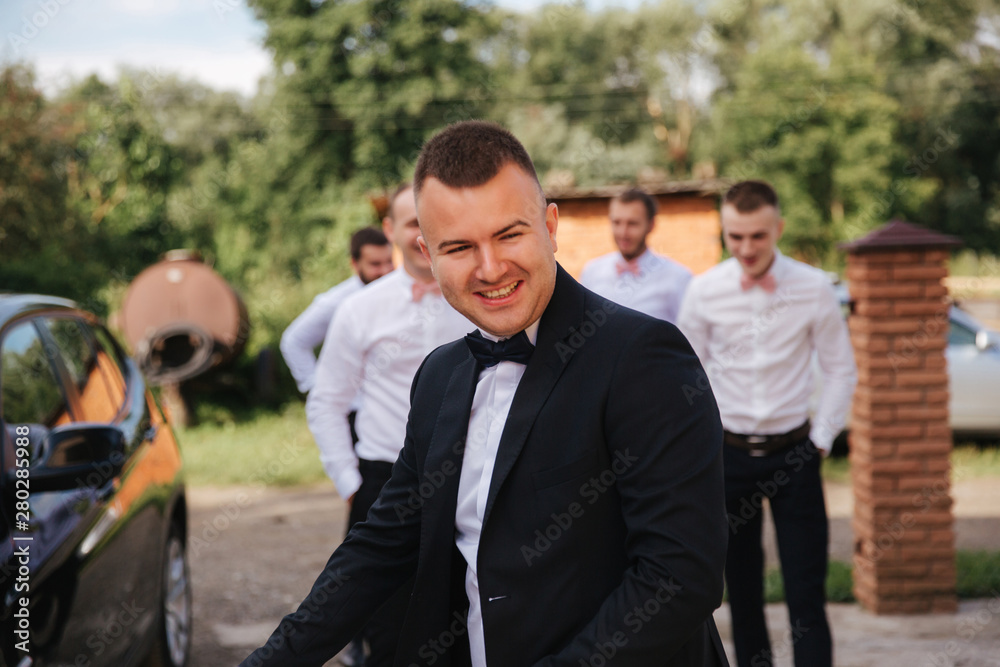 Handsome groom with his groomsman on the backyard. Five man. Groom dressed in suit, gromsmen in white shirt. Funny guys on the wedding Handsome groom with his groomsman on the backyard. Five man. Groom dressed in suit, gromsmen in white shirt. Funny guys on the wedding