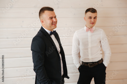 Handsome groom with his groomsman at home. Five man. Groom dressed in suit, gromsmen in white shirt. Funny guys on the wedding photo