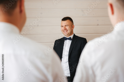 Handsome groom with his groomsman at home. Five man. Groom dressed in suit, gromsmen in white shirt. Funny guys on the wedding photo