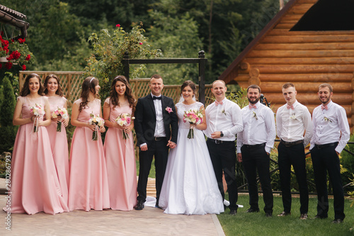 Obraz na plátně Groom and bride stand with groomsman and bridesmaid outside