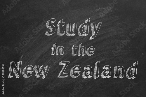 Hand drawing "Study in New Zealand" on black chalkboard. 