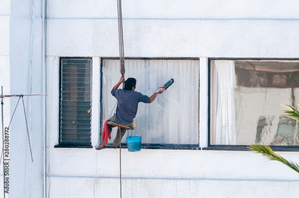 Man cleaning building windows in Mexico City Man cleaning building windows in Mexico City
