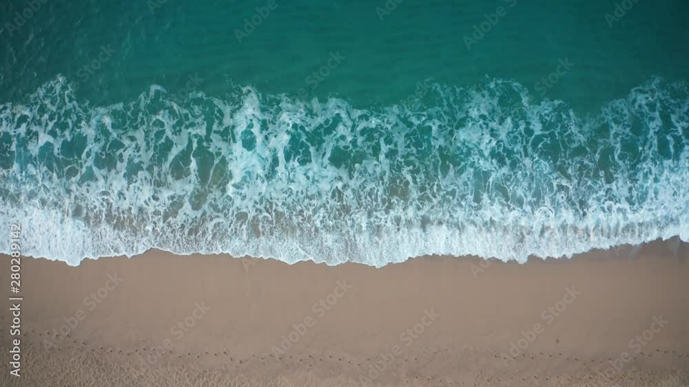 Drone view of beautiful seamless never ending footage while turquiose sea waves breaking on sandy coastline. Aerial shot of golden beach meeting deep blue ocean water and foamy waves