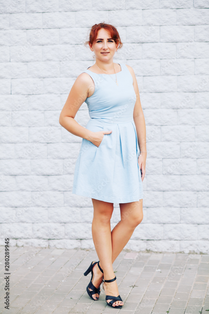 Concept of self-acceptance, body-positive, beautiful young woman in a blue dress walks through the city streets Concept of self-acceptance, body-positive, beautiful young woman in a blue dress walks through the city streets