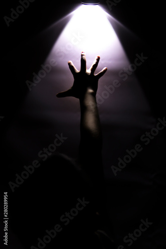 hand reaching up to touch a glowing light