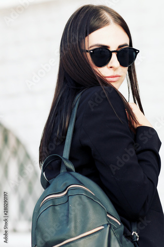 beautiful girl with beautiful girl with brunette hair, posing outside, hipster style, portrait, black jacket, brash girl, sunglasses, street, backpack, Fall fashion