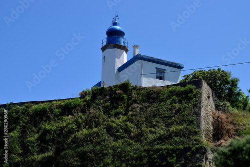 Faro blanco y azul en lo alto de un acantilado.  photo