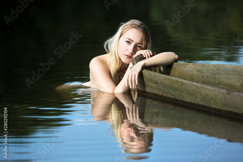 Fototapeta Naklejka Na Ścianę i Meble -  beautiful young woman resting after a swim, holding the edge of a boat