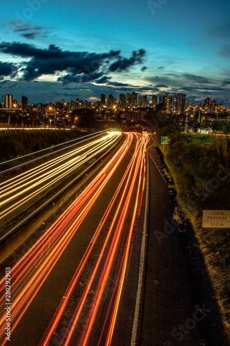 Trail of light caused by vehicular traffic in SP-294, Comandante Joao Ribeiro Barros Highway with buildings from downtown in the background, in Marília, during a late afternoon.