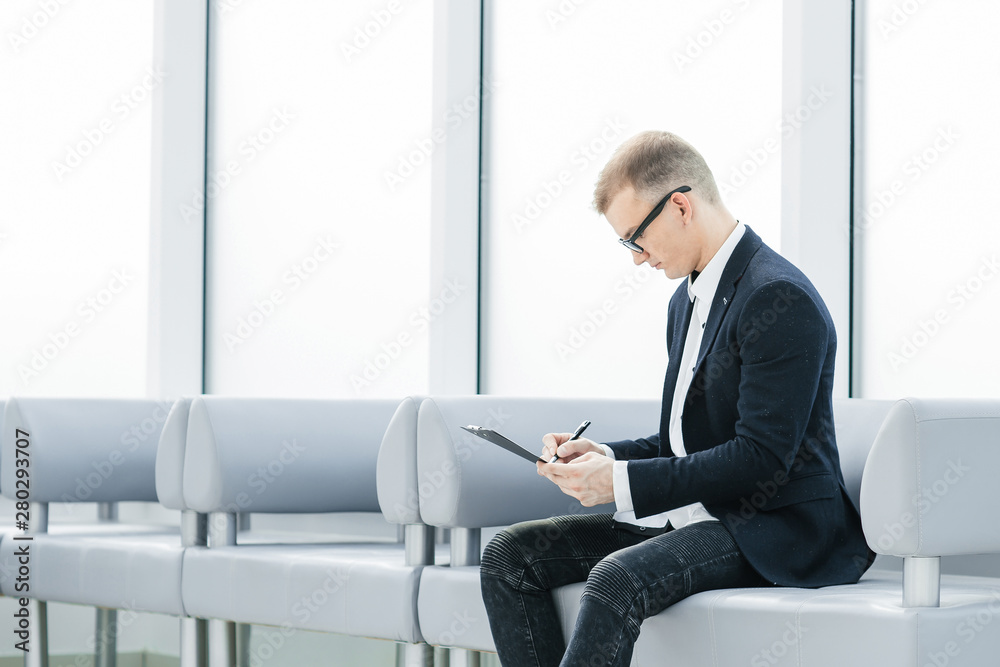 businessman reading a business document sitting in the office lobby