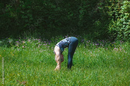 Blonde girl doing stretching yoga pose in the nature. Yoga concept