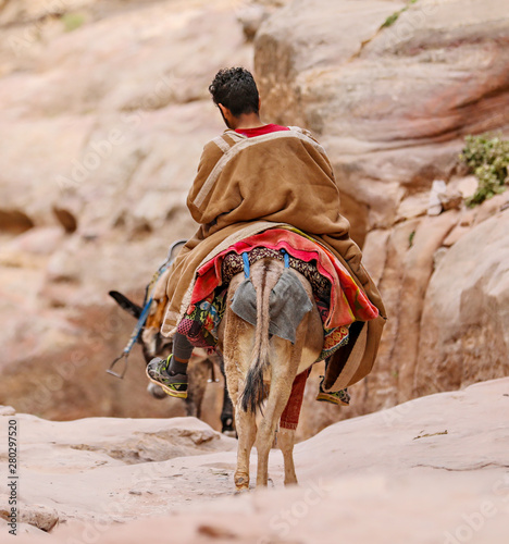 A Bedouin boy rides down the canyon on the back of a donkey in Petra. photo