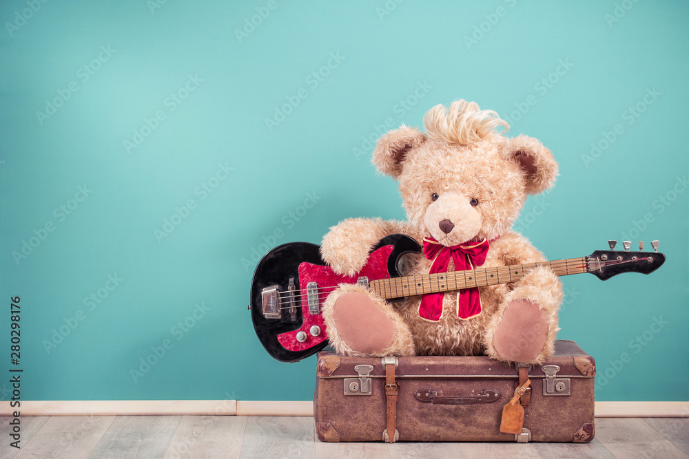 Retro Teddy Bear toy with hairstyle playing bass guitar and sitting on old  leather travel luggage. Hard rock or heavy metal music concept. Vintage  nostalgia style filtered photo Stock Photo | Adobe