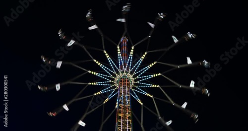 Low angle view of Star flyer, Chain carousel amusement ride, move up and down, and spin around the top of tower with beautiful decorated light on night dark sky background. photo