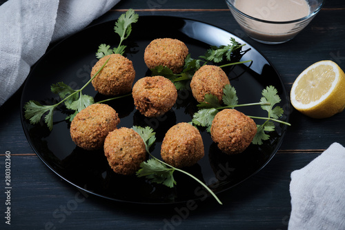 Classic balls of hummus with thina sauce in a plate on a wooden table. National, vegetarian dish, ingredients and cilantro. photo