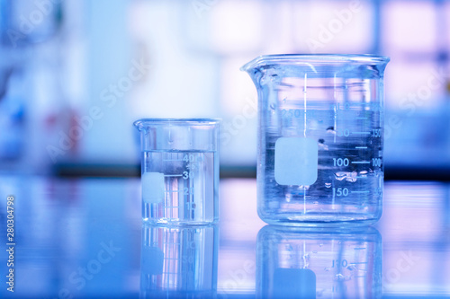 two glass beaker with water in blue medical science laboratory background